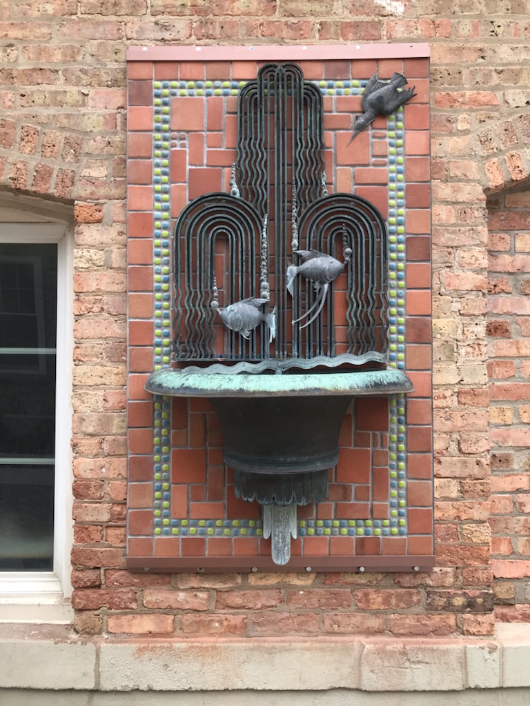 Outdoor wall fountain with fish and water elements in the Art Deco style